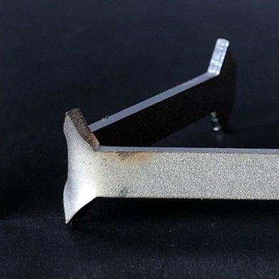 Espeto metálico cinza com régua branca ao lado sobre fundo preto