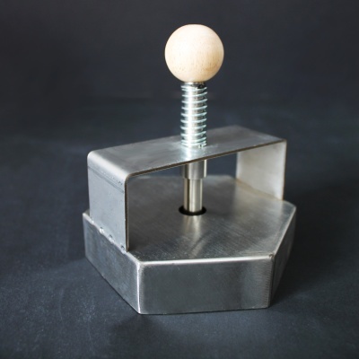 Carimbo metálico hexagonal com haste e botão de madeira em fundo escuro