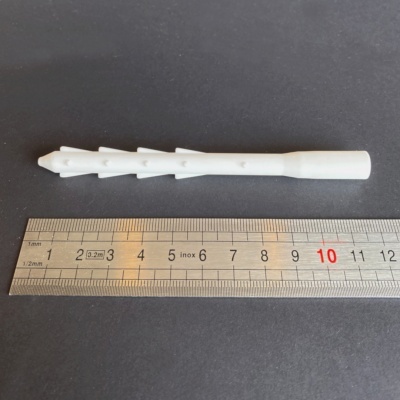 Taco de expansão branco em plástico junto a uma régua de metal.