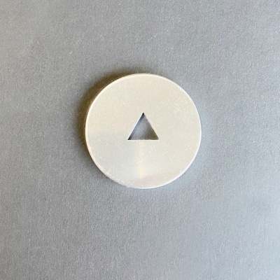 Disco circular branco com triângulo recortado ao centro sobre fundo cinza