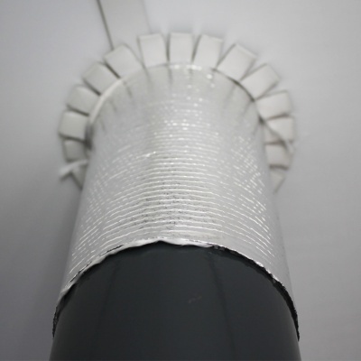 Tubo preto com isolante térmico prateado fixado no teto branco