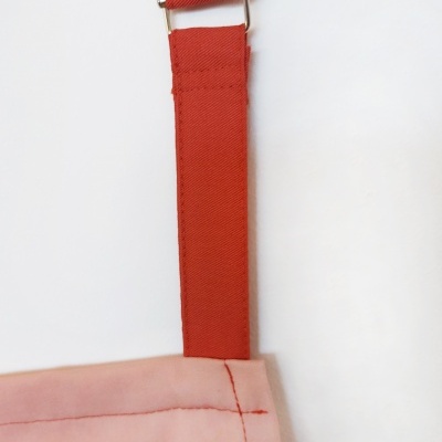 Detalhe de saco rosa com alça vermelha e fivela prateada