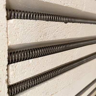 Quatro molas metálicas pretas fixas numa parede branca