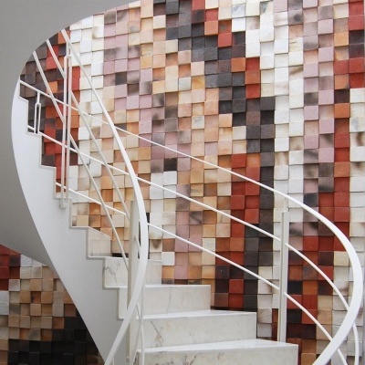 Escada espiral em mármore branco com parede de azulejos coloridos ao fundo