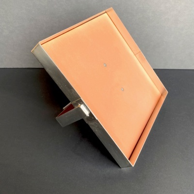 Moldura metálica retangular com parte traseira cor de salmão.