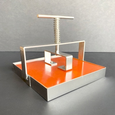 Prensa metálica com base laranja e estrutura prateada