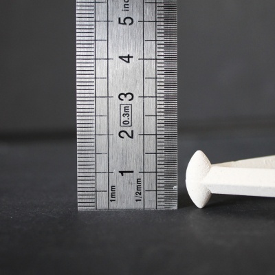 Régua metálica ao lado de peça branca sobre superfície escura