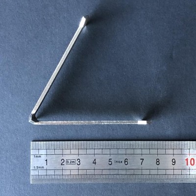 Chave hexagonal metálica e régua inox sobre superfície preta.