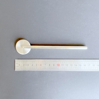 Agulha de relógio branca com régua ao lado sobre superfície cinzenta