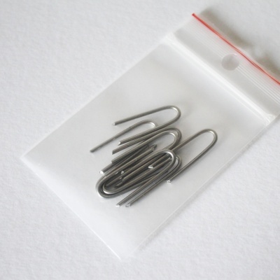 Sacos plásticos transparentes com fecho vermelho e ganchos metálicos prateados