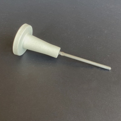 Produto cilíndrico com haste metálica e base cinza sobre superfície preta