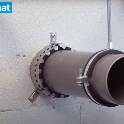 Tubagem cinzenta com suporte metálico instalada numa parede branca e etiqueta 'Promat'