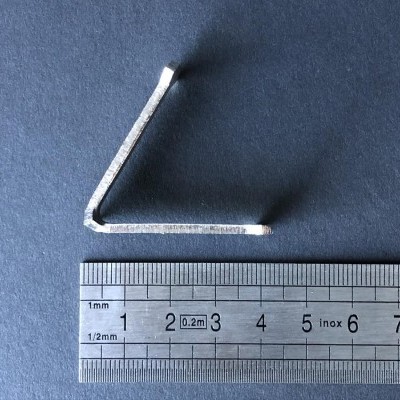 Chave allen metálica prata junto a régua metálica sobre superfície azul escura