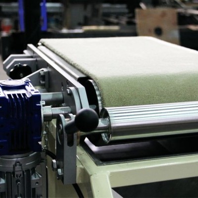 Equipamento industrial com correia transportadora verde e motor azul numa fábrica