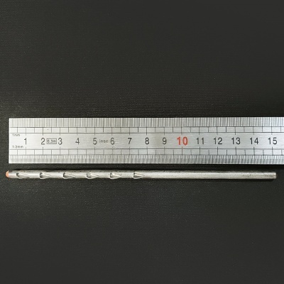 Agulha metálica longa ao lado de régua metálica sobre fundo preto