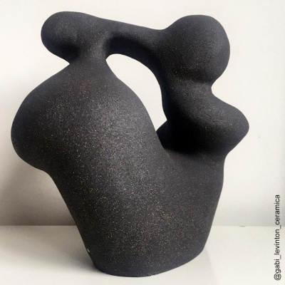 Escultura abstrata em cerâmica preta texturizada com formas curvilíneas.