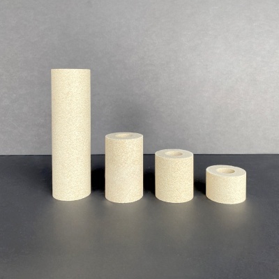 Quatro rolos de fita adesiva bege de vários tamanhos sobre superfície preta e fundo cinzento.