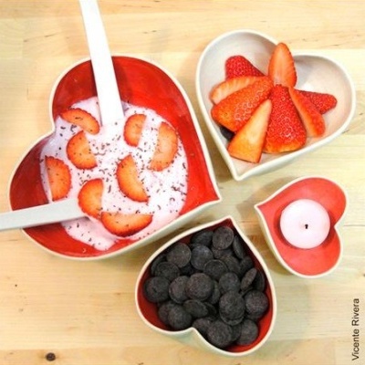 Conjunto de tigelas em forma de coração com morangos, iogurte, chocolate e vela