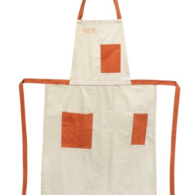 Avental bege com bolsos e alças laranja e palavra 'MATE' bordada no peito