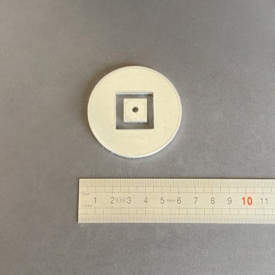 Disco branco redondo com quadrado oco no centro e régua