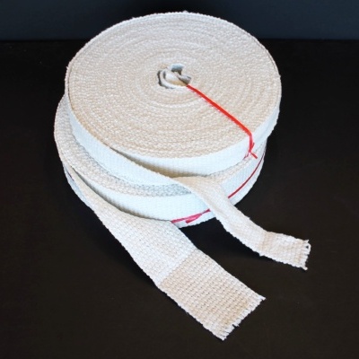 Bobina de faixa têxtil branca enrolada com fio vermelho sobre superfície preta