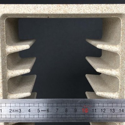 Peça compósito bege com fendas internas e régua metálica de 17 cm à frente