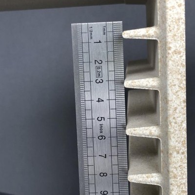 Régua metálica inox junto a superfície de pedra clara com fendas retangulares