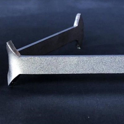 Suporte metálico prateado com textura mate junto a régua sobre fundo escuro