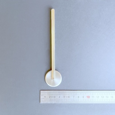 Colher de plástico transparente com cabo amarelo claro ao lado de régua metálica