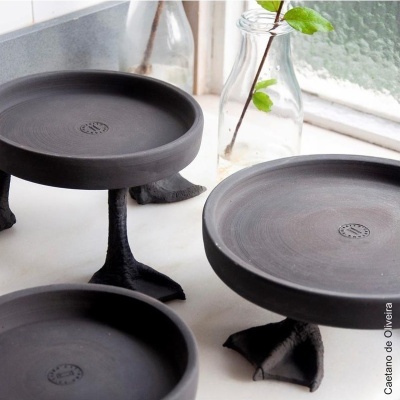 Bases pretas com pés em forma de patas de aves em tampo branco próximo a vidro com ramo verde