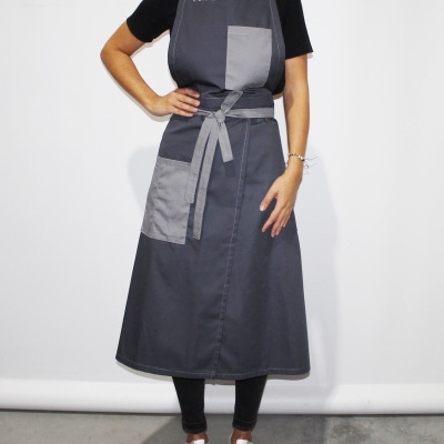 Pessoa com avental cinza escuro com bolso cinza claro em fundo branco.