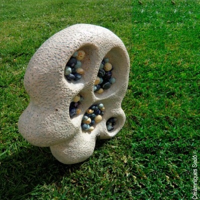 Escultura orgânica em pedra com pequenas pedras coloridas em cavidades