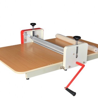 Mesa de trabalho com rolo de material branco e manivela vermelha