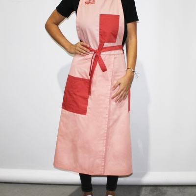 Avental rosa com bolsos e detalhes vermelhos usado por uma modelo em fundo branco