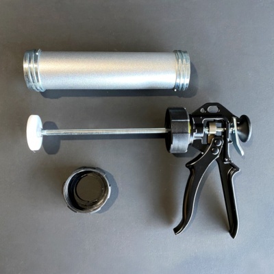 Equipamento para aplicação de selante com cilindro metálico prateado e partes pretas