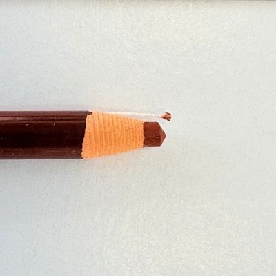 Lápis de carvão castanho com cordel branco na ponta