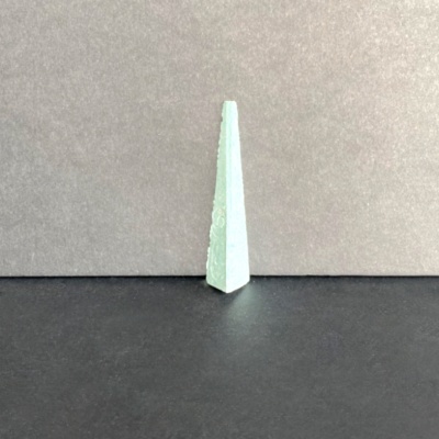 Objeto triangular branco sobre superfície preta e fundo cinzento