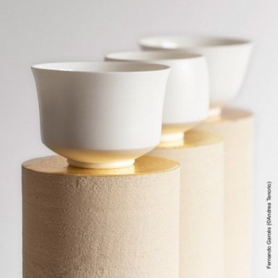 Três chávenas brancas em suportes cilíndricos bege