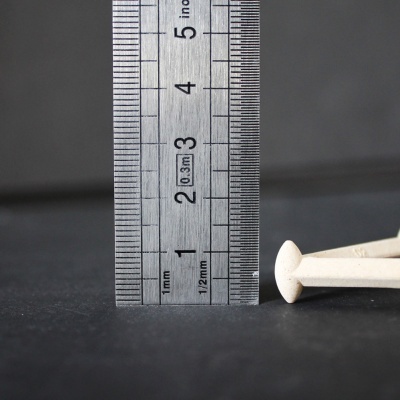 régua metálica ao lado de pregos brancos sobre superfície preta