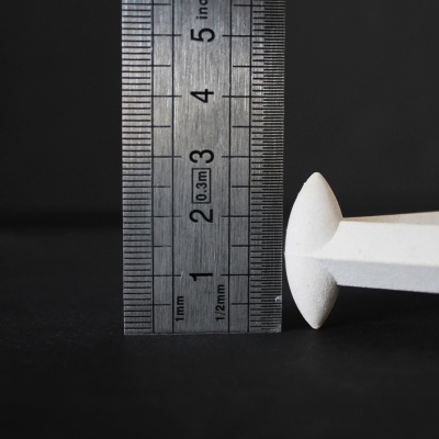 Régua metálica ao lado de prego branco sobre fundo preto