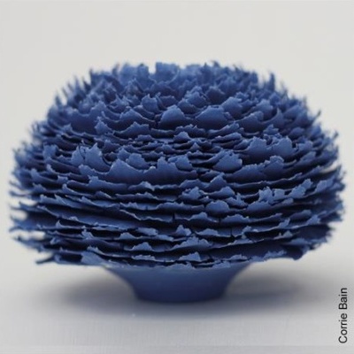 Escultura azul com textura em camadas sobre superfície branca