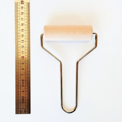 Rolo de pintura e régua metálica sobre fundo branco