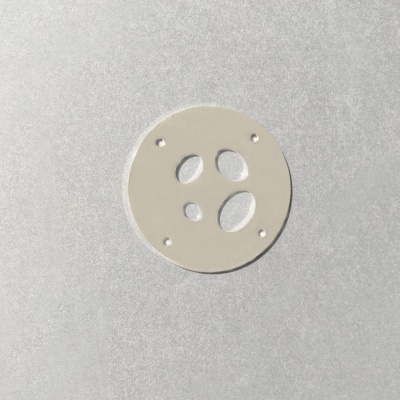 Disco redondo branco com orifícios em superfície cinza