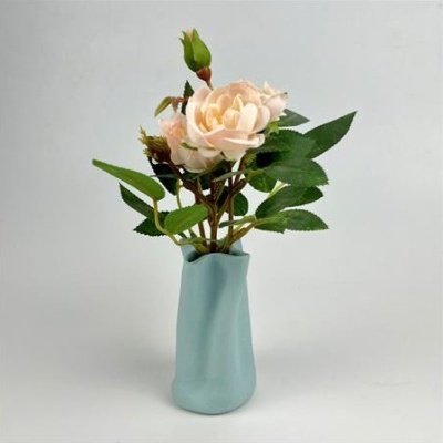 Vaso cerâmico azul claro com rosa artificial cor de rosa e folhas verdes