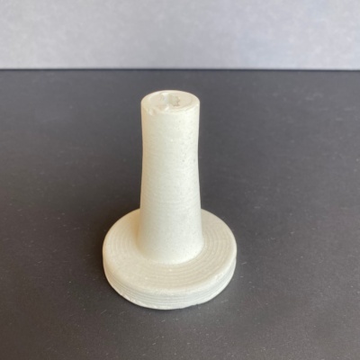 Objeto branco com base circular e coluna cilíndrica em superfície preta