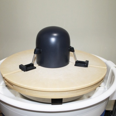 Suporte ou acessório de cozinha com base circular de madeira clara e objeto preto no centro