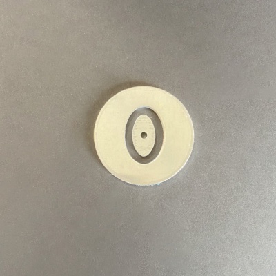 Objeto circular branco e cinzento com orifício ao centro, em superfície cinzenta