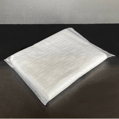 Pacote transparente com manta branca texturada sobre superfície preta