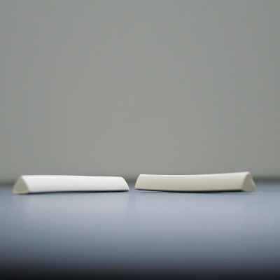 Dois objetos brancos alongados sobre superfície cinzenta