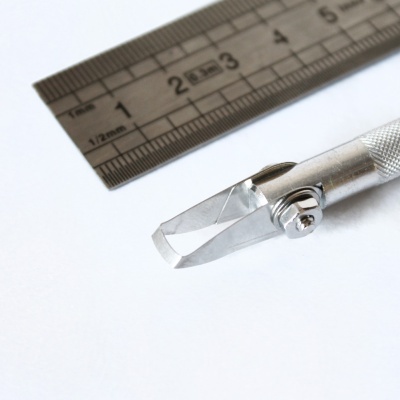 Estilete metálico com régua de metal sobre fundo branco